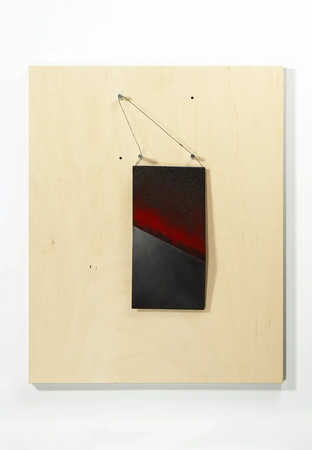 A small copper sculpture hanging from a wood backing panel by artist Gaylia Wagner